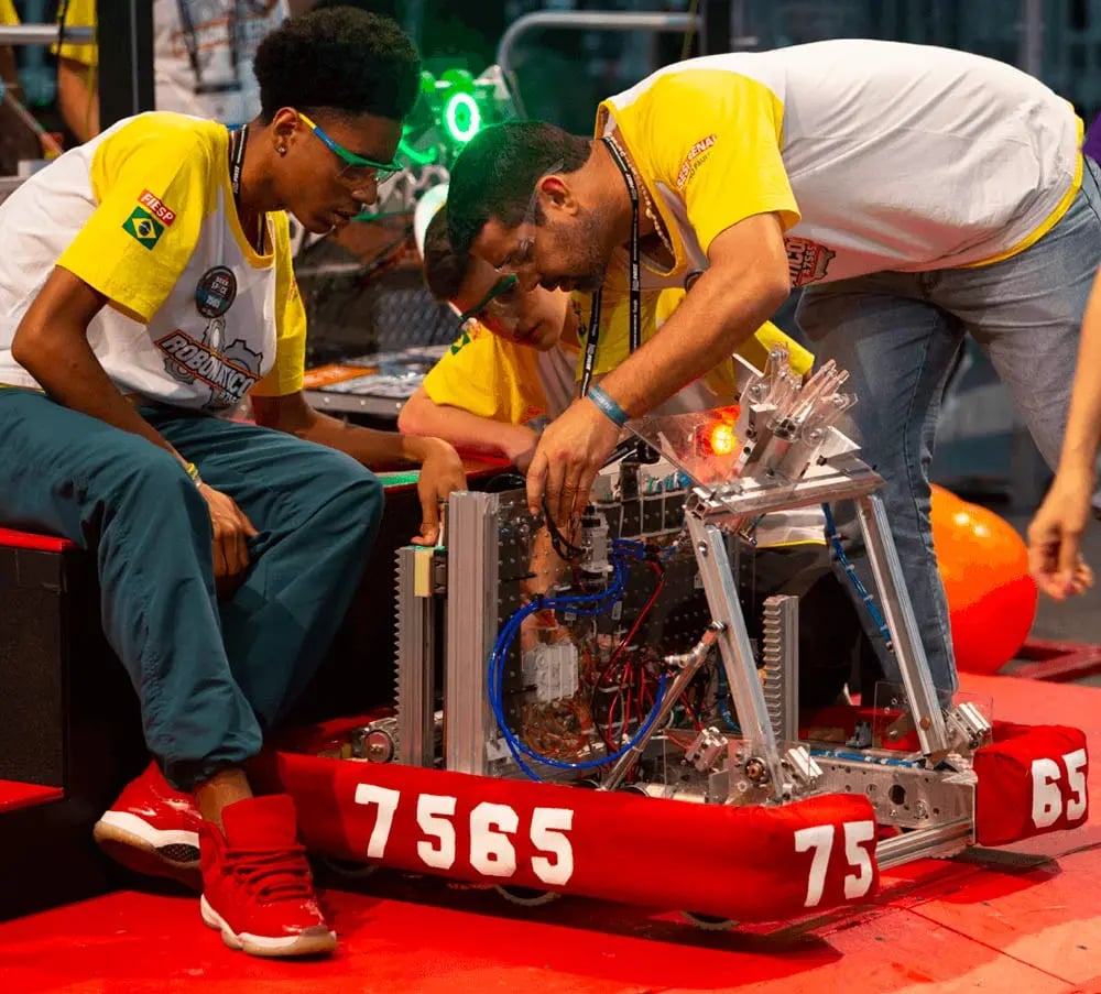 FIRST Robotics Competition participants make adjustments to robot